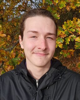 Das Bild zeigt ein Foto im Porträt-Format von Marvin Wiederanders vor einem Eichenbaum